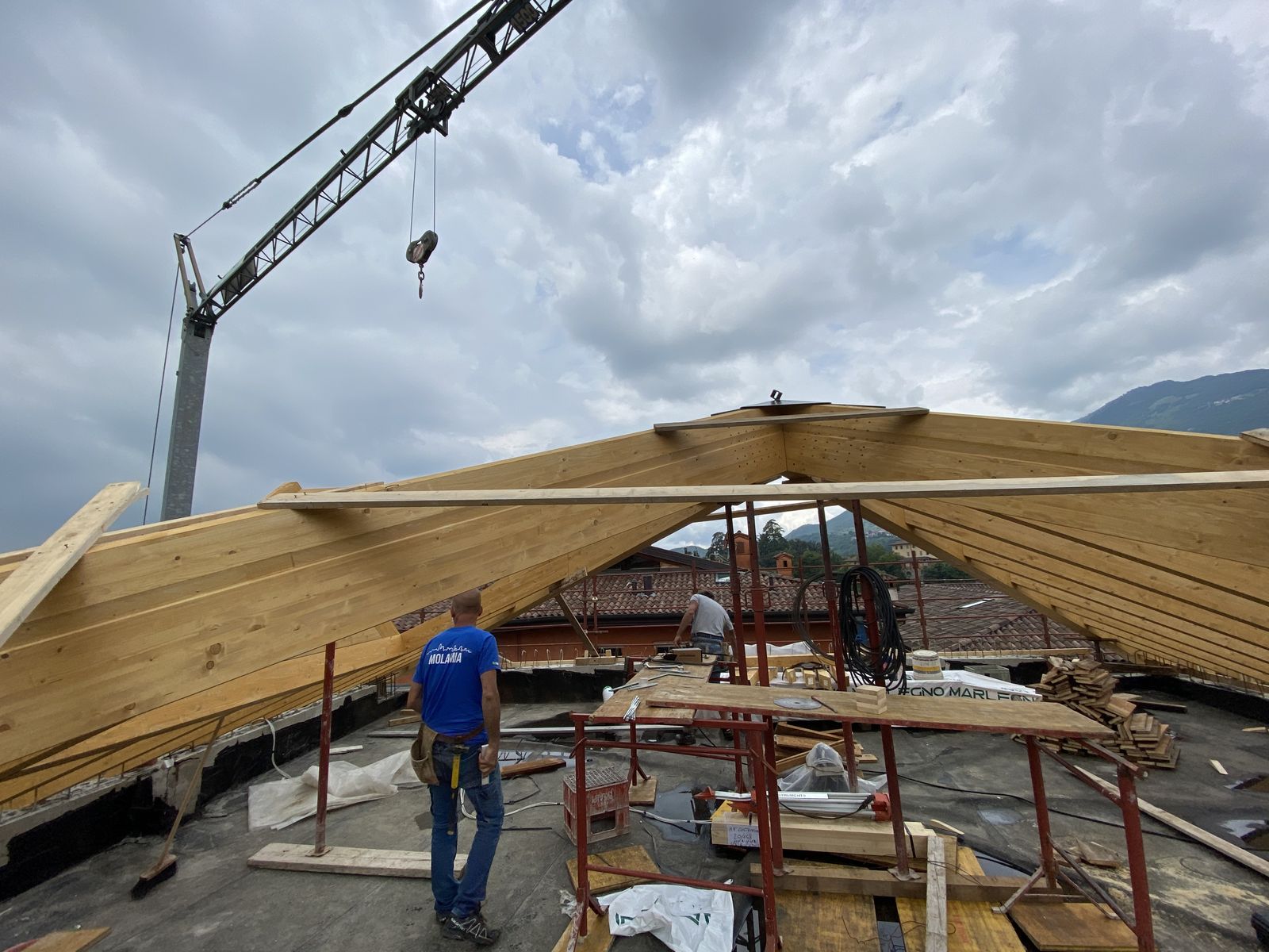 La struttura del tetto in legno di un nostro edificio residenziale, con la gru e un operaio