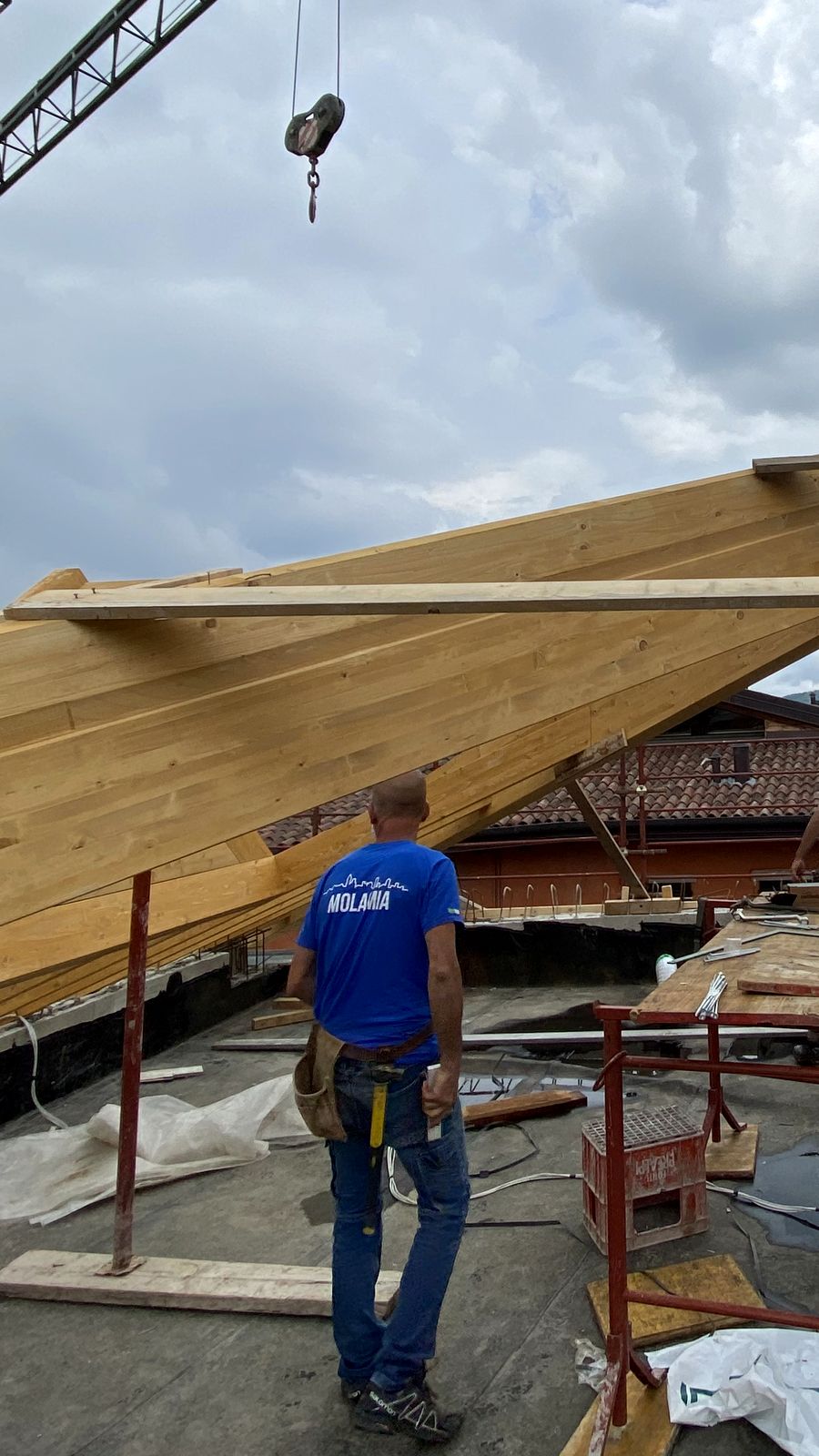 La struttura del tetto in legno di un edificio residenziale, con la gru e un operaio