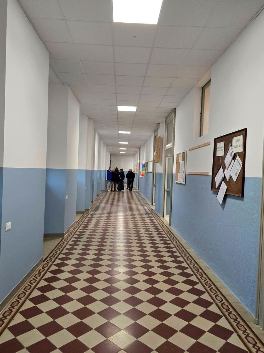 Corridoio di un edificio pubblico con pavimento a scacchi rosso e bianco e pareti azzurre